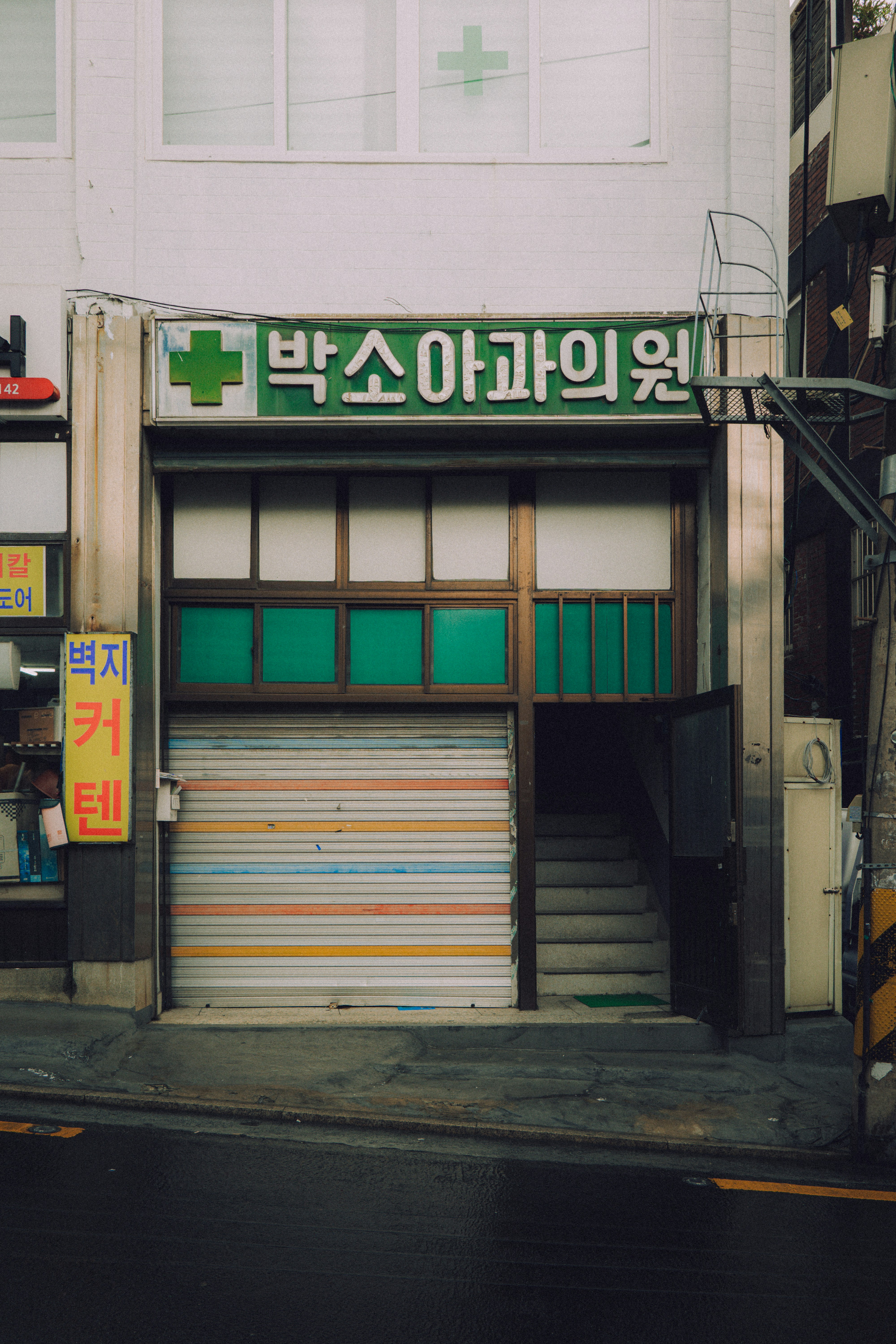 A closed storefront with korean signage and green accents